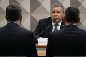 Ilustração gerada por inteligência artificial de audiência da CPMI, com dois homens de terno vistos de costas e depoente ao microfone.