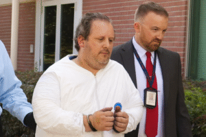 Anthony Todt é escoltado por agentes após julgamento nos Estados Unidos. Imagem otimizada por inteligência artificial para fins jornalísticos.