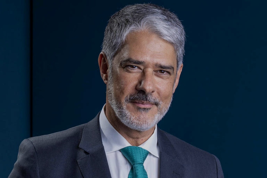 Jornalista William Bonner em retrato de estúdio, com terno escuro e fundo azul. Imagem adaptada por inteligência artificial.