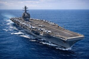 Porta-aviões USS Gerald R. Ford navega em mar aberto com aeronaves militares posicionadas no convés em operação naval no Caribe.