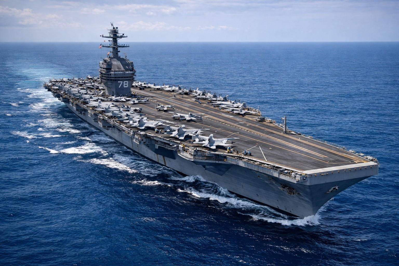 Porta-aviões USS Gerald R. Ford navega em mar aberto com aeronaves militares posicionadas no convés em operação naval no Caribe.