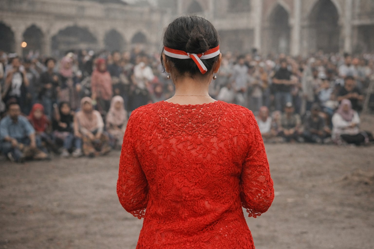 Mulher vista de costas em praça pública, diante de um grupo de pessoas, em cena ilustrativa.