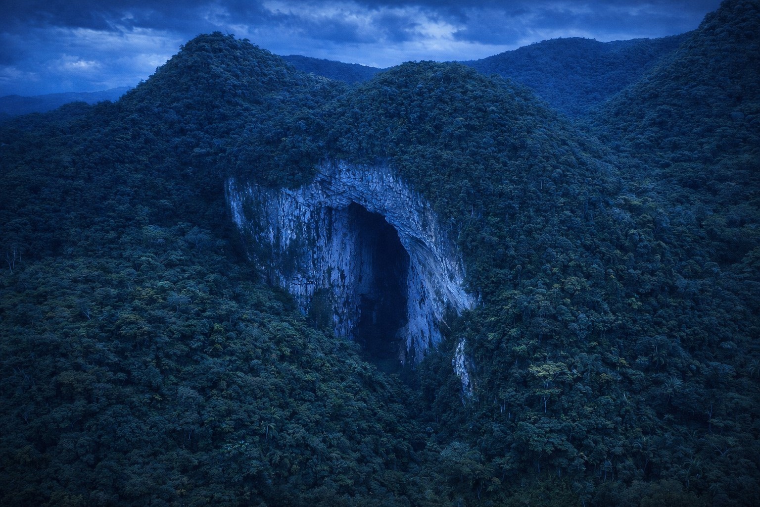 Entrada da caverna Casa de Pedra vista do alto, cercada por mata densa no interior de São Paulo.
