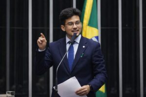 Deputado federal discursando na Câmara dos Deputados, em Brasília, durante sessão plenária, em imagem fotográfica otimizada por IA.