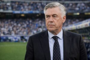 Ilustração fotográfica ultrarrealista de Carlo Ancelotti de terno e gravata em ambiente característico de estádio de futebol, gerada por inteligência artificial.