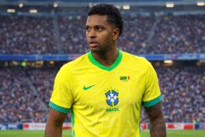 Imagem gerada por IA mostra o atacante Rodrygo com uniforme da Seleção Brasileira em estádio de futebol, utilizada para contextualização de notícia esportiva.