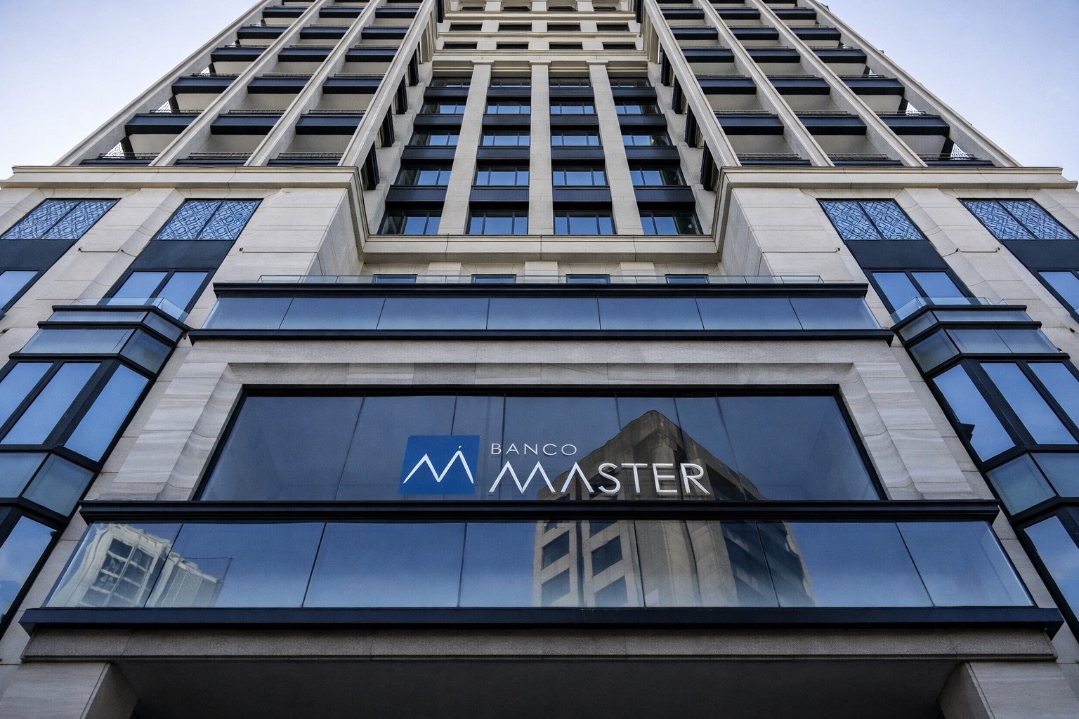 Fachada de edifício com a marca Banco Master vista de baixo para cima. Imagem baseada em fotografia real da instituição financeira e otimizada por inteligência artificial para melhoria de resolução, utilizada para contextualização jornalística.