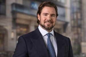 Retrato de Daniel Vorcaro em primeiro plano, com fundo desfocado que remete à fachada do Banco Master.