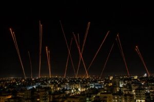 Vista noturna de Beirute com rastros luminosos no céu durante celebração de cessar-fogo.