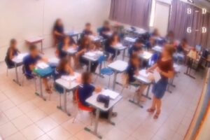 Imagem de reprodução de câmera de segurança mostra professora em sala de aula da rede municipal de Potirendaba (SP), com alunos sentados e rostos desfocados.
